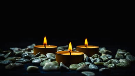 Velas acesas sobre pedras escuras, ambiente de massagem Nuru em Lisboa